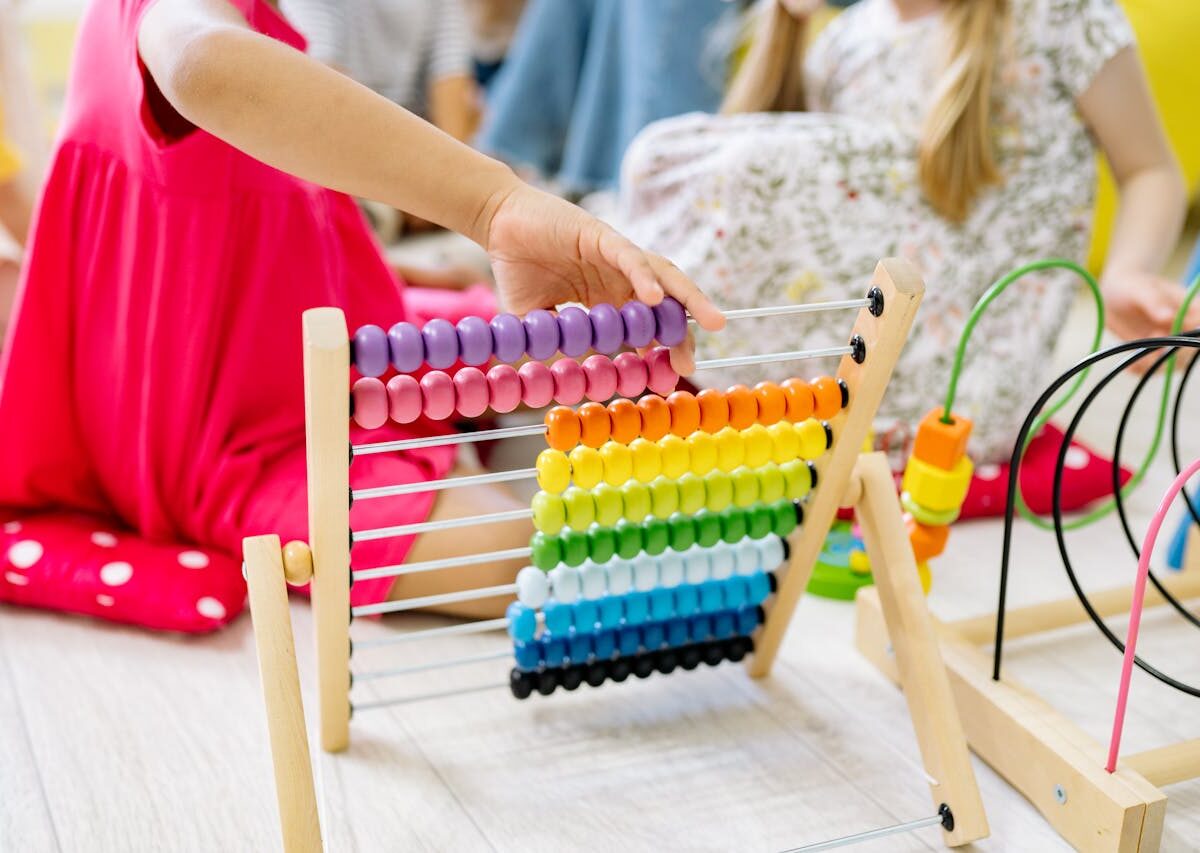 Children actively learning with a colorful abacus in a preschool setting, enhancing educational fun.